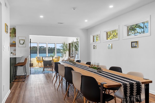 dining room featuring recessed lighting, a water view, visible vents, and wood finished floors