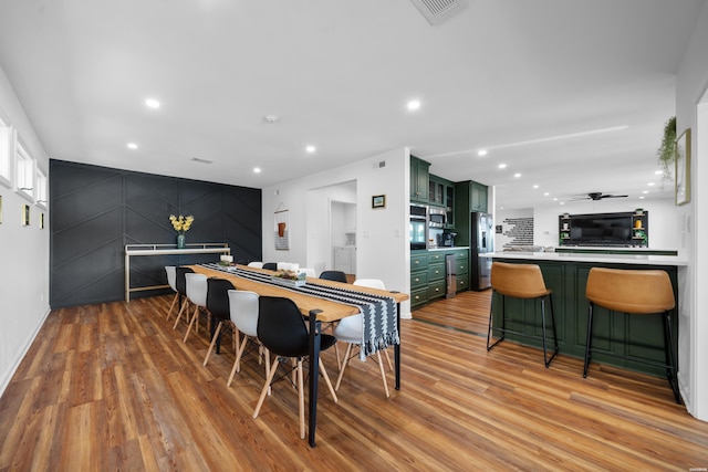 dining space with recessed lighting, visible vents, light wood-style flooring, a ceiling fan, and an accent wall