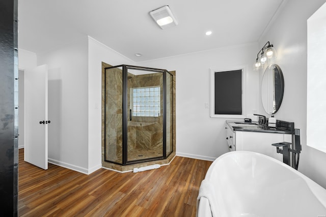 bathroom with a stall shower, crown molding, baseboards, and wood finished floors