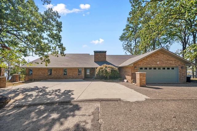 single story home featuring a garage, concrete driveway, brick siding, and a chimney