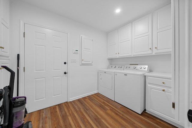 clothes washing area featuring dark wood-type flooring, washing machine and dryer, cabinet space, and baseboards