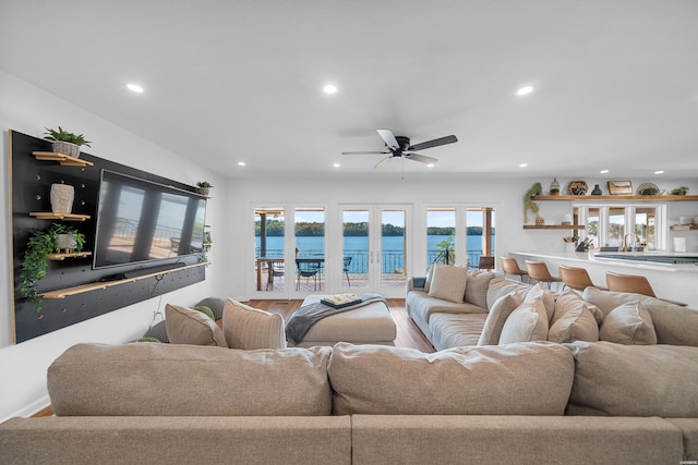 living room with a ceiling fan, recessed lighting, a water view, and wood finished floors