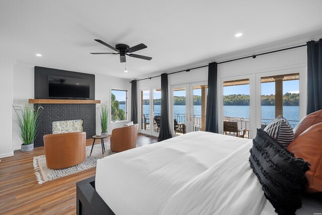 bedroom featuring access to exterior, a fireplace, wood finished floors, and french doors