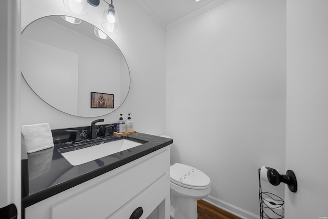 bathroom with crown molding, toilet, vanity, wood finished floors, and baseboards