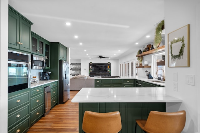 kitchen featuring appliances with stainless steel finishes, light countertops, a peninsula, and a breakfast bar area