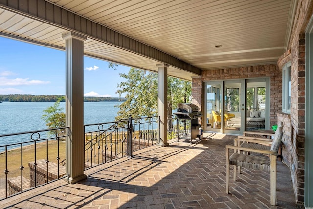 view of patio featuring a water view, a grill, and a balcony