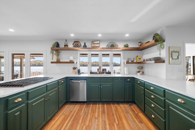 kitchen featuring stainless steel appliances, light countertops, a sink, and open shelves