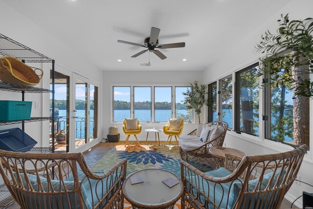 sunroom featuring a water view, ceiling fan, and visible vents