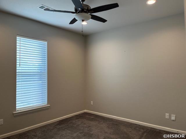 unfurnished room with ceiling fan, dark colored carpet, and baseboards