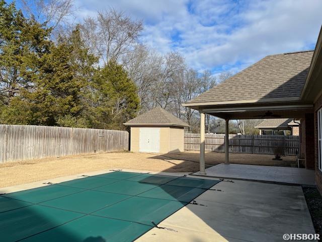 view of swimming pool featuring a storage shed, a patio, an outbuilding, and a fenced backyard