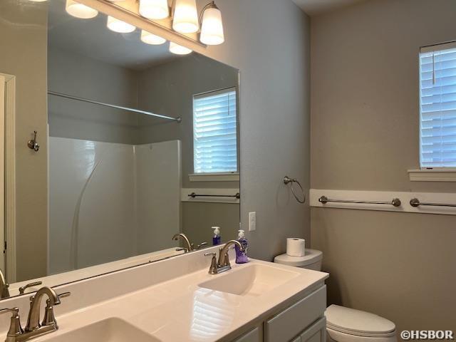 full bath with a sink, toilet, and double vanity