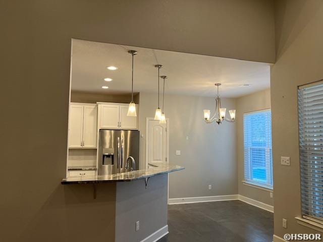 kitchen featuring hanging light fixtures, stainless steel refrigerator with ice dispenser, white cabinetry, and a kitchen breakfast bar