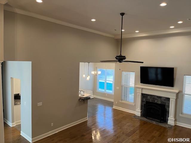unfurnished living room featuring baseboards, a fireplace with flush hearth, dark wood finished floors, and crown molding