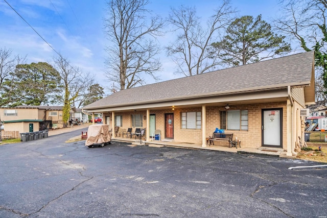 view of front of home with brick siding and roof with shingles