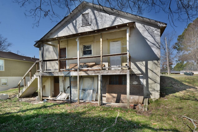 rear view of property with stairway and a yard