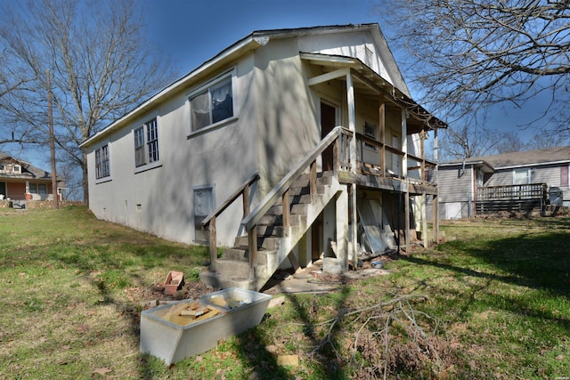 back of property featuring stairway, stucco siding, a wooden deck, and a yard