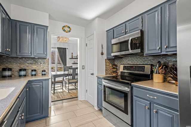 kitchen featuring appliances with stainless steel finishes, light countertops, blue cabinetry, and tasteful backsplash