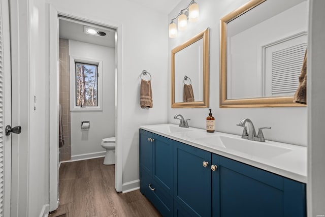 full bathroom featuring double vanity, a sink, baseboards, and wood finished floors