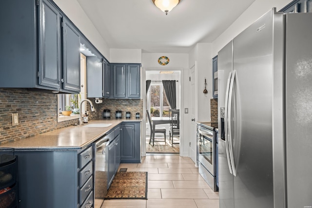 kitchen featuring stainless steel appliances, tasteful backsplash, light countertops, light tile patterned flooring, and a sink