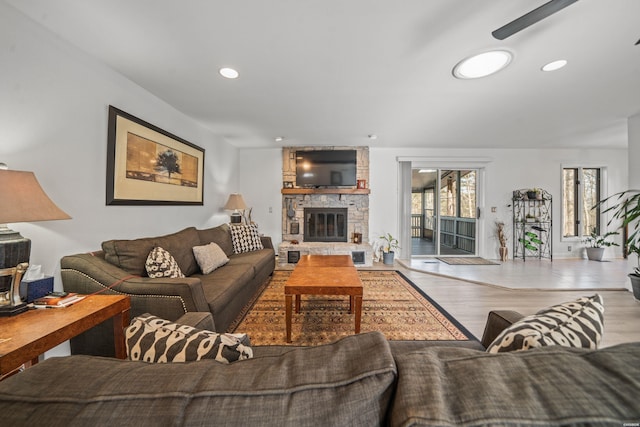 living area with a stone fireplace, wood finished floors, and recessed lighting