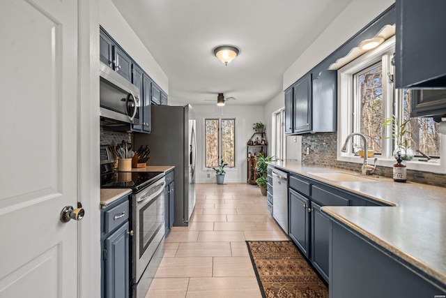 kitchen featuring tasteful backsplash, appliances with stainless steel finishes, light countertops, and a sink