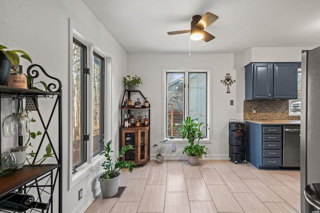 interior space featuring light countertops, decorative backsplash, appliances with stainless steel finishes, a ceiling fan, and baseboards