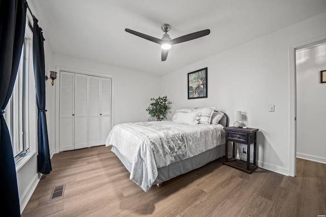 bedroom with a closet, visible vents, a ceiling fan, wood finished floors, and baseboards