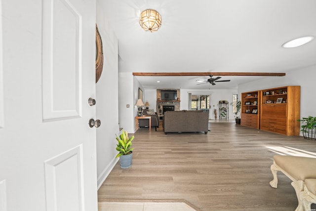 entryway with light wood finished floors, a fireplace, a ceiling fan, and baseboards