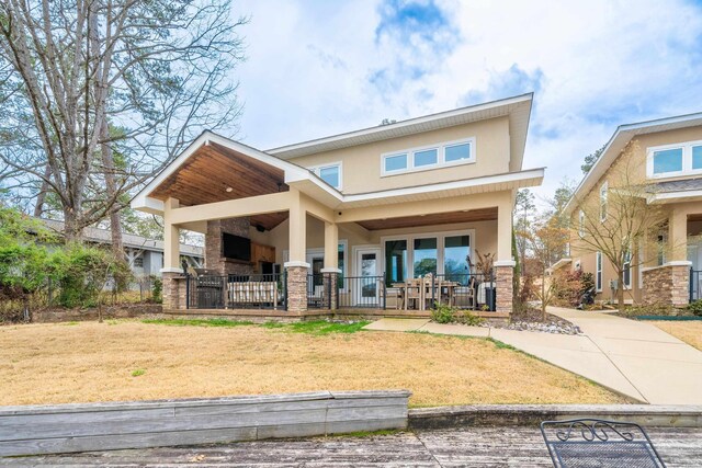 back of house featuring a porch, a yard, and stucco siding