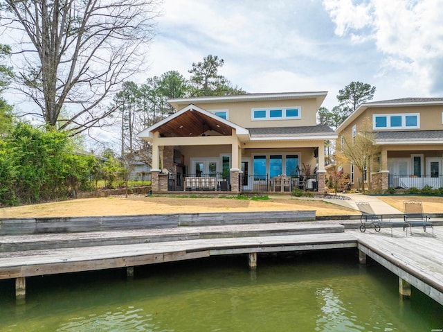 back of property featuring a water view and stucco siding