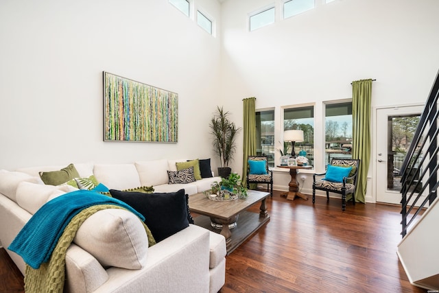 living area with a high ceiling, dark wood-style flooring, and stairway