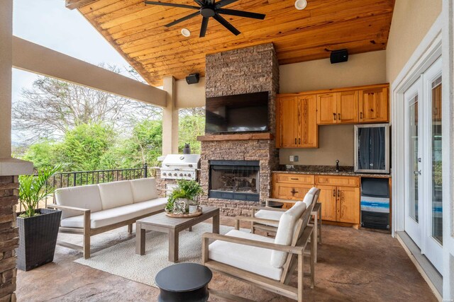 view of patio with a ceiling fan, a grill, and an outdoor living space with a fireplace