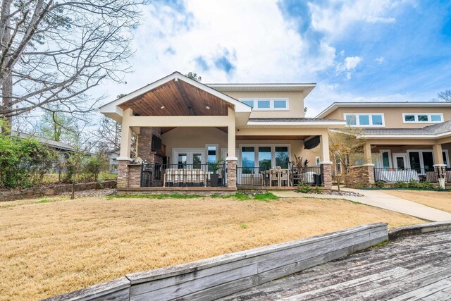 back of property featuring a yard, french doors, a porch, and stucco siding