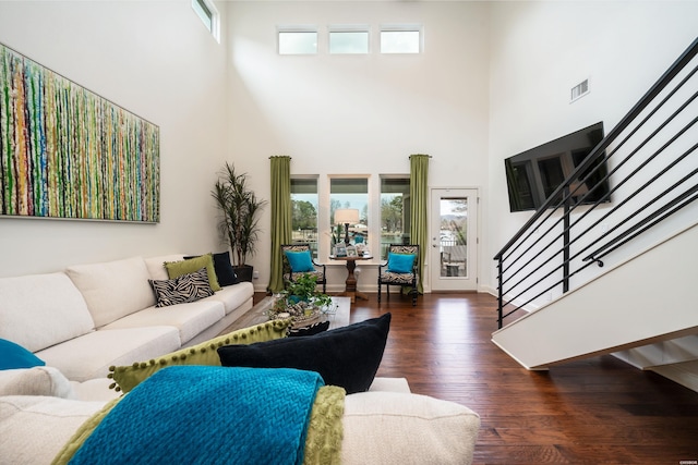 living area featuring visible vents, a high ceiling, stairway, and dark wood-type flooring