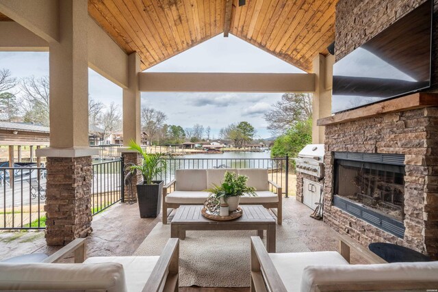 view of patio featuring area for grilling, an outdoor living space with a fireplace, a water view, and a grill