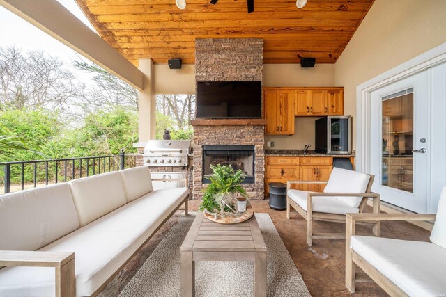 view of patio / terrace with a ceiling fan, a sink, grilling area, and an outdoor living space with a fireplace