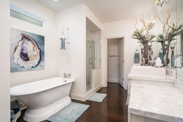 full bath featuring a soaking tub, vanity, a shower stall, wood finished floors, and baseboards