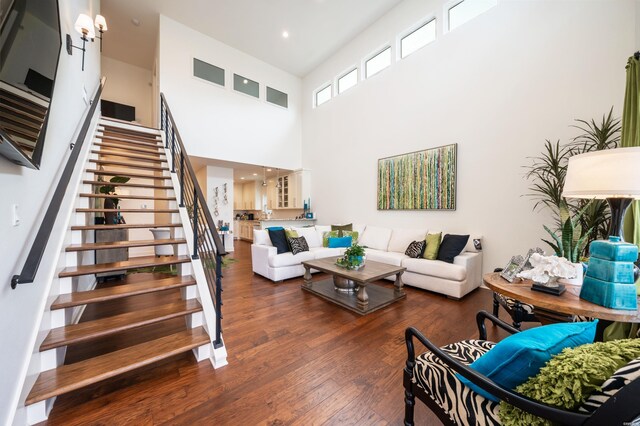 living area featuring recessed lighting, dark wood-type flooring, a high ceiling, visible vents, and stairway