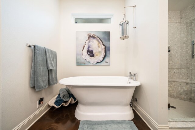 full bathroom featuring a stall shower, baseboards, wood finished floors, and a soaking tub