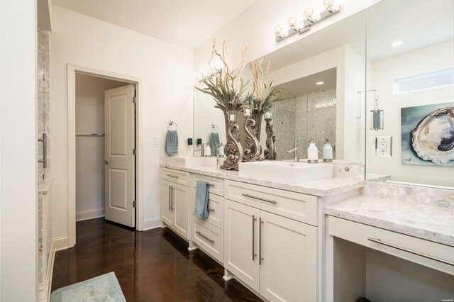 bathroom with double vanity, recessed lighting, a sink, wood finished floors, and baseboards