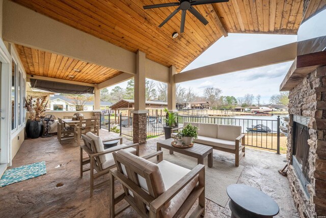 view of patio featuring a water view, outdoor dining area, an outdoor hangout area, and a ceiling fan