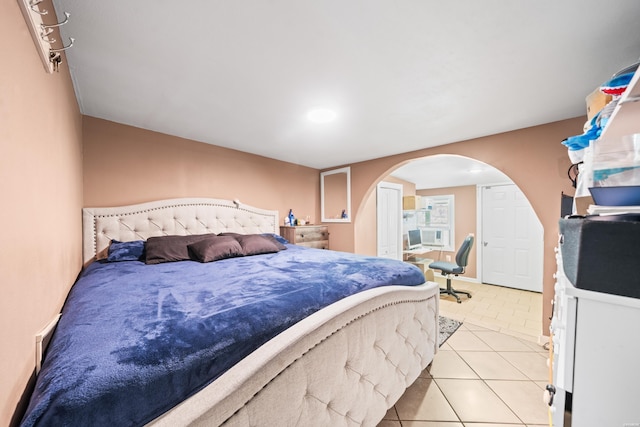 bedroom featuring arched walkways and light tile patterned flooring