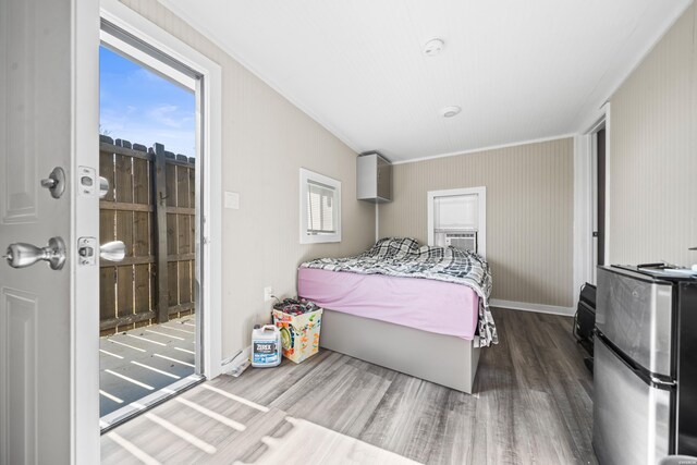 bedroom with freestanding refrigerator, baseboards, wood finished floors, and ornamental molding