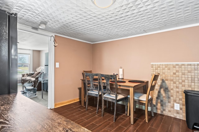 dining space with wood finish floors, crown molding, and baseboards