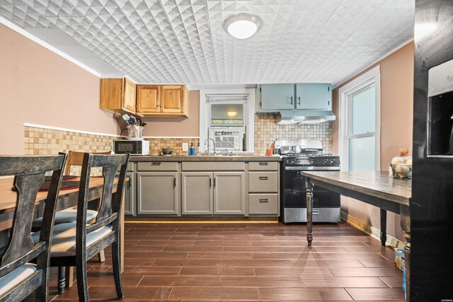 kitchen with tasteful backsplash, wood tiled floor, stainless steel gas stove, plenty of natural light, and exhaust hood