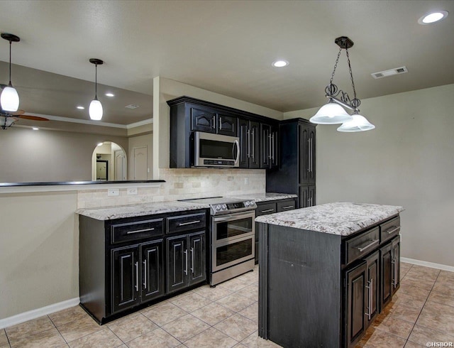 kitchen with appliances with stainless steel finishes, dark cabinets, visible vents, and pendant lighting