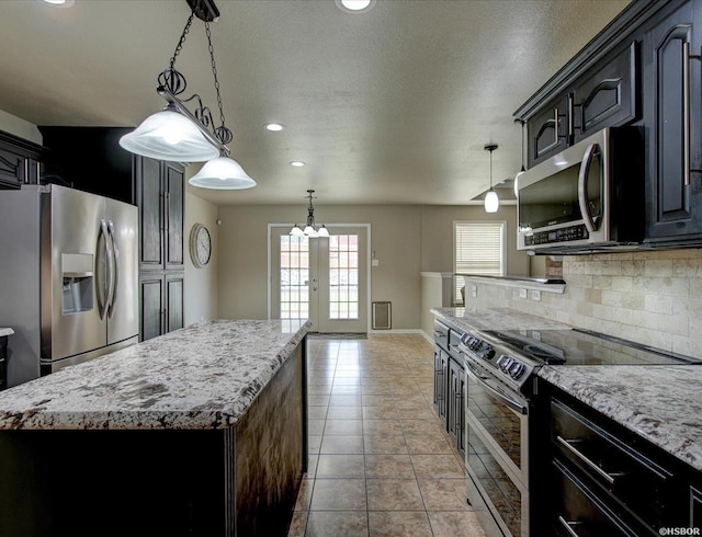 kitchen featuring pendant lighting, french doors, stainless steel appliances, tasteful backsplash, and a kitchen island