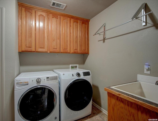 clothes washing area with cabinet space, visible vents, washer and clothes dryer, a sink, and light tile patterned flooring