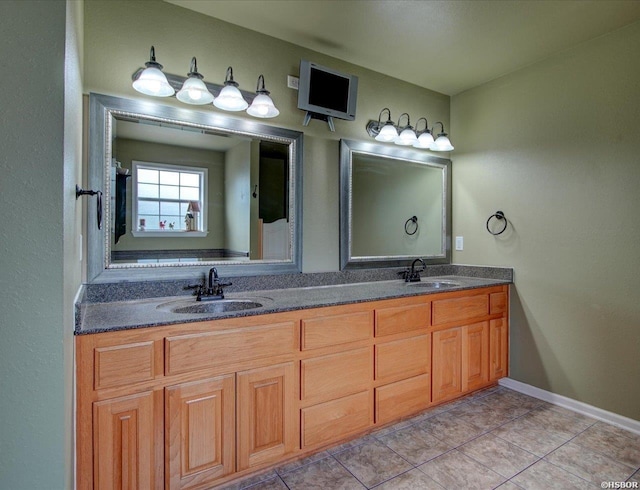 full bath with double vanity, baseboards, a sink, and tile patterned floors