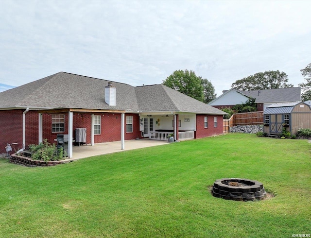 back of house featuring brick siding, an outdoor fire pit, fence, a shed, and an outdoor structure